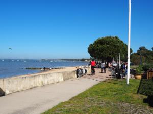 a group of people riding bikes on a sidewalk near the water at La Flibuste in Andernos-les-Bains +5 photos