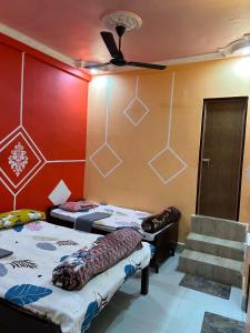 a room with two beds and a ceiling fan at Snehalata Lodge in Badarpur
