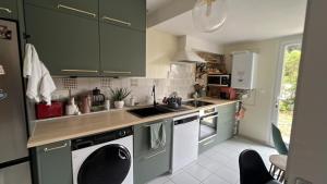 a kitchen with green cabinets and white appliances at Les Charmilles in Aytré
