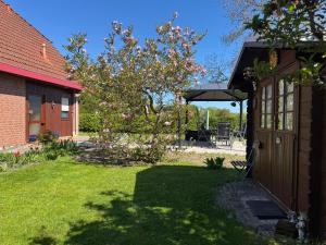 a yard with a house and a tree with pink flowers at Ferienwohnung am Borgwallsee in Steinhagen