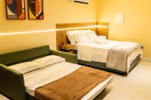 a hotel room with two beds and a couch at Loft moderno e aconchegante no coração de Icaraí in Niterói