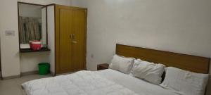 a bedroom with a bed with white sheets and pillows at Hotel Shyam in Agra