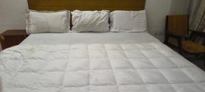 a bed with white sheets and pillows at Hotel Shyam in Agra