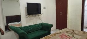 a living room with a green couch and a flat screen tv at Hotel Shyam in Agra