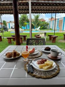 a table with plates of food and drinks on it at Pousada Villa Japa in Maragogi