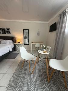 a bedroom with a glass table and two white chairs at The Ceed in Beacon Bay