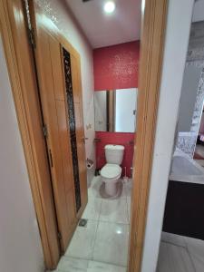 a bathroom with a toilet and a red wall at Apartment Konouz Meknes in Meknès +17 photos
