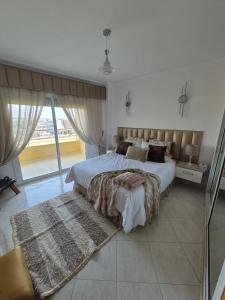 a bedroom with a large bed and a large window at Apartment Konouz Meknes in Meknès