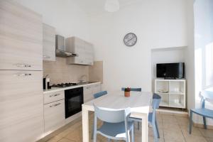 a kitchen with a white table and blue chairs at Pozzallo yellow house,5'dal mare in Pozzallo +22 photos