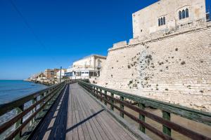 a wooden boardwalk next to a building next to the water at Pozzallo yellow house,5'dal mare in Pozzallo