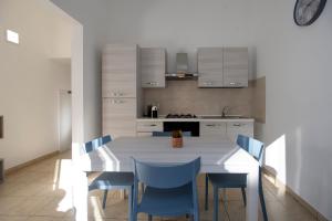 a kitchen with a white table and blue chairs at Pozzallo yellow house,5'dal mare in Pozzallo