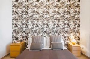 a bed with two pillows and a patterned wall at Aranci 99 House in Sorrento