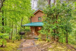 a cabin in the woods with a porch and a grill at Precious Moments in Sevierville