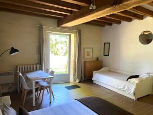 a bedroom with a bed and a table and a window at L'Aveneau - Havre champêtre avec piscine d'été in Le Retail