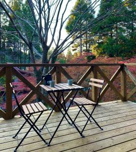 a table and two chairs on a wooden deck at Lodge Kurokawa 1 in Minamioguni