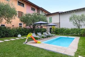 a pool with a slide and chairs and an umbrella at Le Logge del Garda in San Felice del Benaco