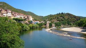 a view of a river with houses and a bridge at Jasmin et Camomille in Roquebrun