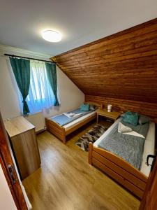 zwei Betten in einem Zimmer mit Holzdecke in der Unterkunft Vila ILKA in Praid