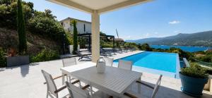 a white table and chairs next to a swimming pool at Villa Haut Standing Stella Di Mare vue panoramique in Propriano