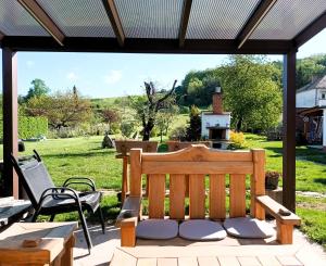 a patio with a wooden bench and a chair at Chalupa U Vinaře in Radějov