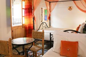 a bedroom with a bed and a table and chairs at Riad Fes EL KAID in Fez