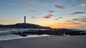 a lighthouse on a island in the ocean at sunset at E21 The Sandy Heaven in Lossiemouth
