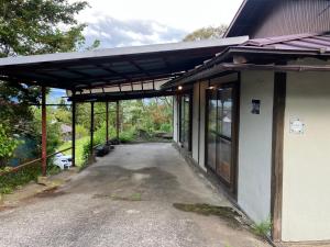 a building with a covered walkway next to a road at 一棟貸ひなたぼっこくらなみ in Nagano