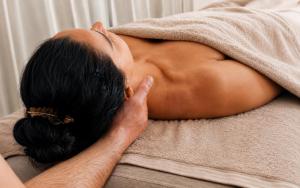 a woman laying on a towel on a bed at Hôtel Les Magnanarelles in Maussane-les-Alpilles
