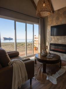 a living room with a couch and a table and a large window at Boutique Cabin with Strait of Magellan Views in Punta Arenas