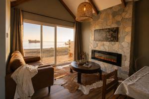 a living room with a fireplace and a view of the ocean at Boutique Cabin with Strait of Magellan Views in Punta Arenas