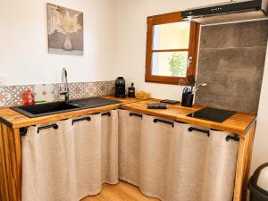 a kitchen with a sink and a counter with curtains at Entre parenthèses - Grand confort et Parking privé in Le Fousseret