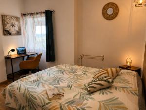 a bedroom with a bed and a desk with a laptop at Entre parenthèses - Grand confort et Parking privé in Le Fousseret