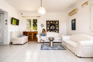 a woman sitting on a couch in a living room at Sea View Retreat in Oxílithos