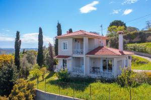 a white house on a hill with trees at Sea View Retreat in Oxílithos