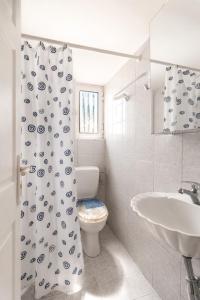 a bathroom with a toilet and a sink and a shower curtain at Sea View Retreat in Oxílithos +14 photos