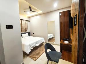 a bedroom with a bed and a chair and a mirror at Maa Ambika Royal House in Baripāda