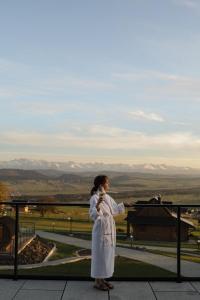 a woman in a white robe looking out at the mountains at Gorczański Lux Chalet in Szlembark