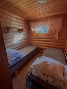 a bedroom with two beds in a log cabin at Kalliorinteen Mökit Ruskapirtti in Töysä