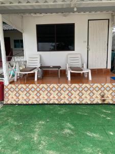 a patio with two chairs and a table on a house at Koh Samed Lungdam Hutbeach เกาะเสม็ดลุงดำฮัทบีช in Ao Phutsa