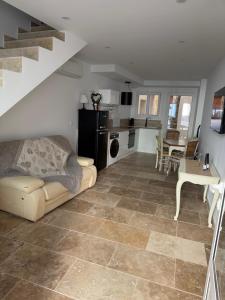 a living room with a couch and a kitchen and stairs at Les remparts de Sasha in Lapalme