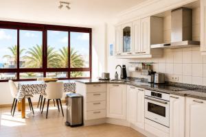 a kitchen with white cabinets and a table with chairs at La Casa del Toro in Corralejo