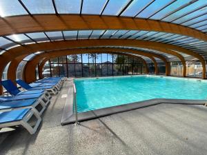 a large swimming pool with blue chairs and a ceiling at Ocean Lodge Messanges in Messanges