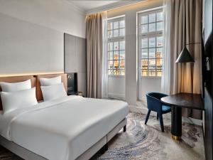 a hotel room with a bed and a desk and window at Mövenpick Grand Hotel Wroclaw in Wrocław