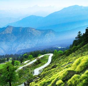 a winding road on a hill with mountains in the background at Shree Kedar dham Guest House in Gupta Kāshi