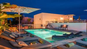 a swimming pool with chairs and an umbrella at Villa Santa Rosa - Conforto e lazer com piscina e zona de jogos em Armação de Pêra in Armação de Pêra