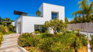 a white house with a garden in front of it at Villa Santa Rosa - Conforto e lazer com piscina e zona de jogos em Armação de Pêra in Armação de Pêra