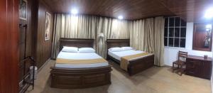 a bedroom with two beds and a table and a desk at mithwood in Nuwara Eliya