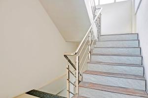 a staircase in a home with white walls and wooden stairs at Super Collection O Baner Formerly Seven Hills in Pune +28 photos
