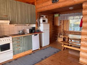 a kitchen with white appliances and a table in a cabin at Kalliorinteen Mökit Havupirtti in Töysä
