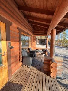 a porch of a log cabin with a couch and a chair at Kalliorinteen Mökit Havupirtti in Töysä